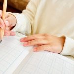 ノートに字を書いている子どもの手の周辺写真