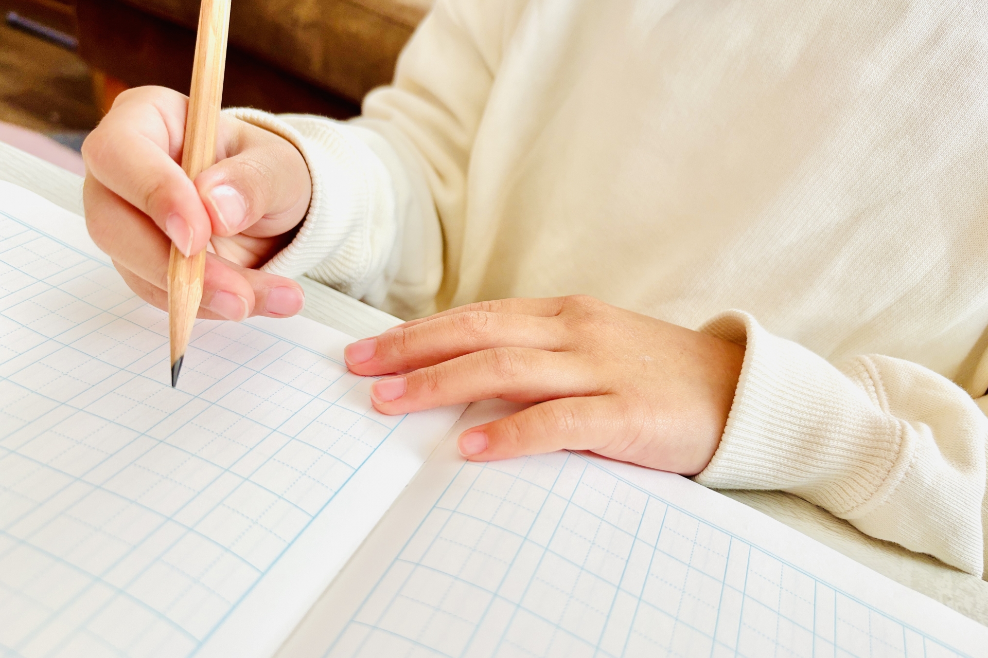 ノートに字を書いている子どもの手の周辺写真