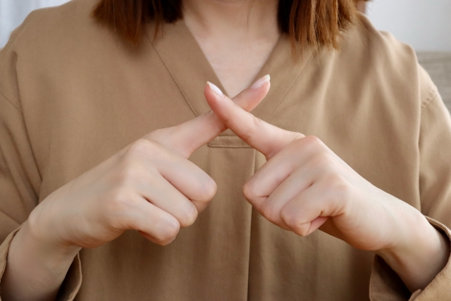 指で×を示す女性