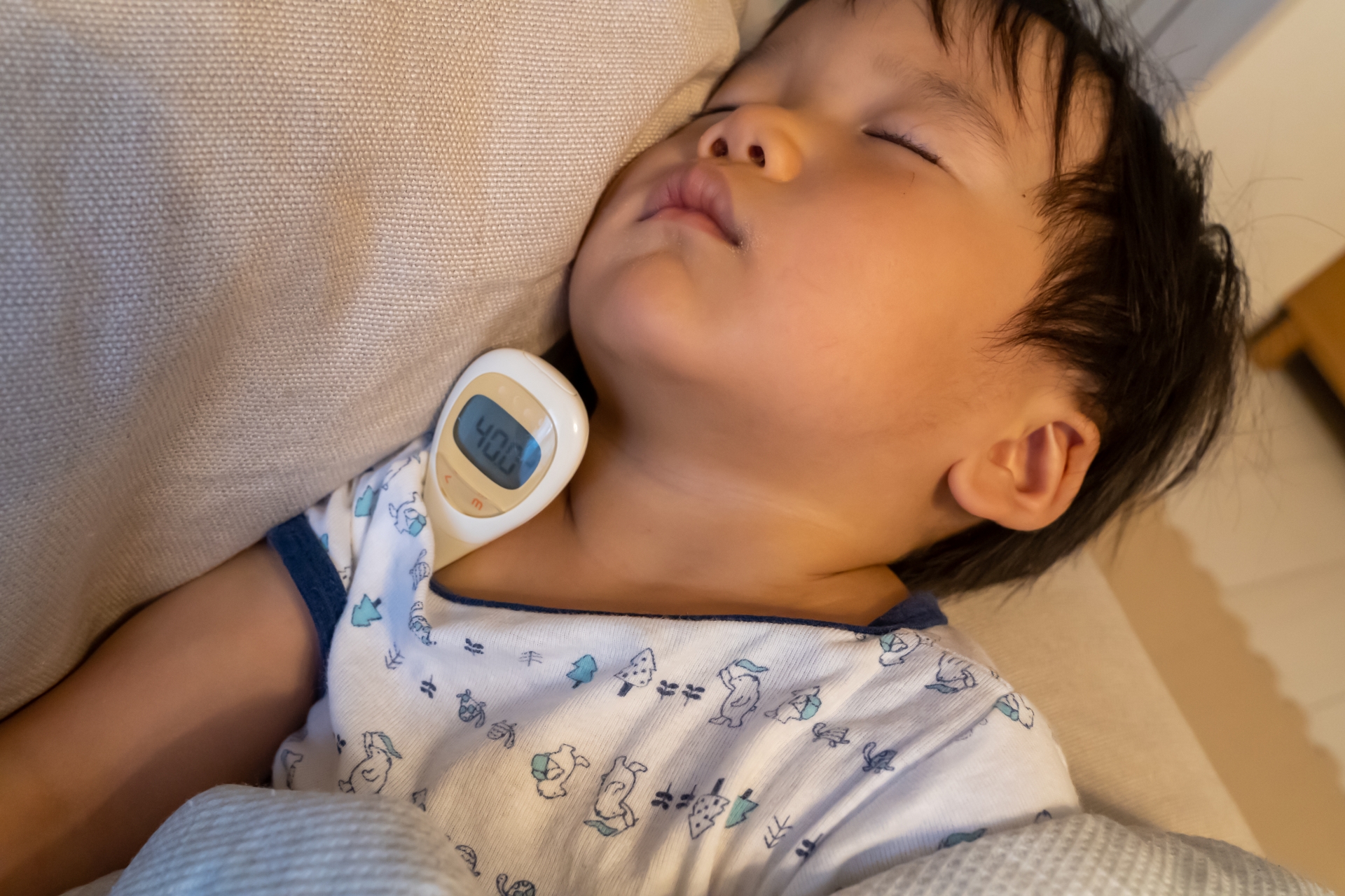 体温計で熱を測っている子供